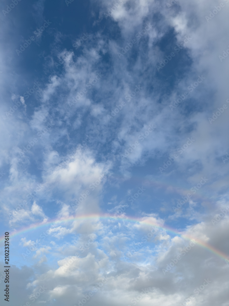 Obraz premium Beautiful rainbow in the blue sky with white clouds