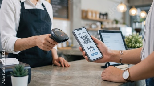 Customer scanning QR code on smartphone screen to pay for order at cafe counter while barista holds payment terminal, contactless mobile transaction concept.