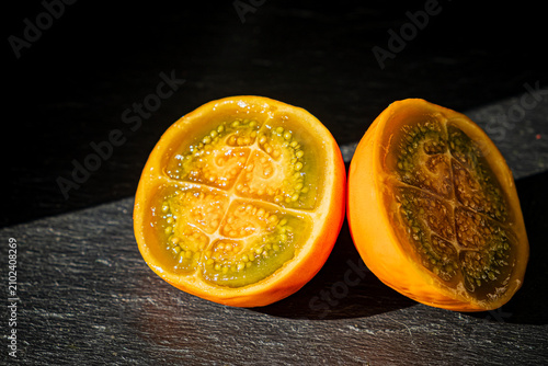 Bright and vibrant slices of fresh sapote on a dark background