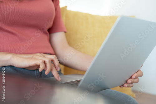 Photography Woman sitting on sofa using laptop on her lap, working at at home, surfing the n
