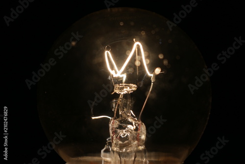 Foto Close up of a glowing vintage incandescent light bulb filament in the dark