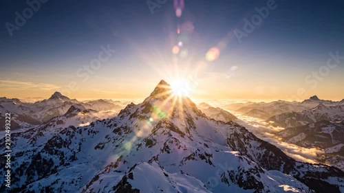 Snowy mountain peak under golden sunrise sky