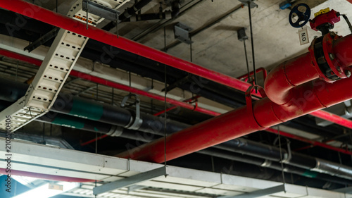 Bild auf Leinwand Fire sprinkler system with red water supply pipes installed on a building ceiling