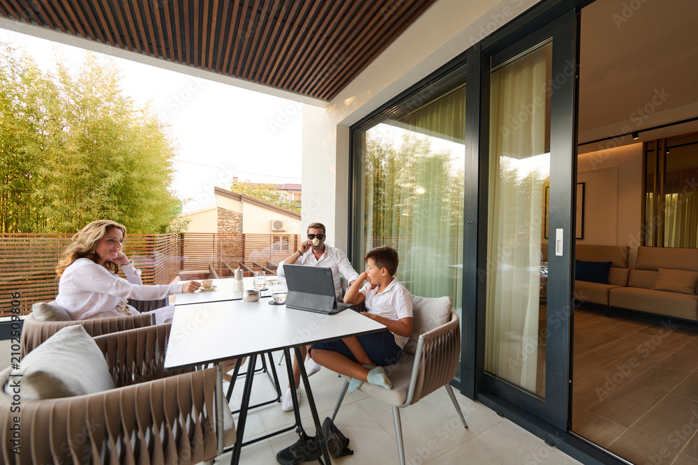 Obraz premium Family Working and Relaxing on a Home Balcony Terrace With Laptop, Coffee and Casual Conversation