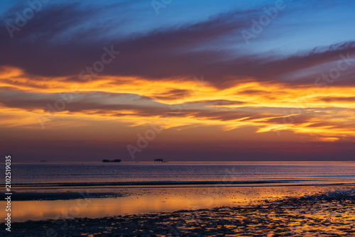 Beautiful coastal sunrise landscape with vibrant blue and orange gradient background.
