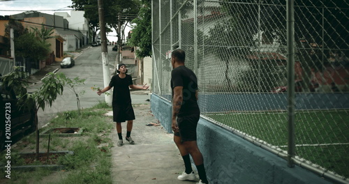 Принти на полотні Two Hispanic men confronting each other on urban street near soccer court, stand