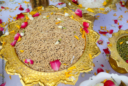 Fotografie A golden tray of unhusked rice and mung beans prepared for a traditional Brahman-Hindu and Thai worship ceremony, symbolizing abundance, prosperity, growth, and good fortune