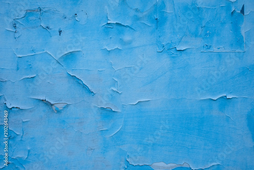 An old wall painted bright blue with peeling paint, urban textured background