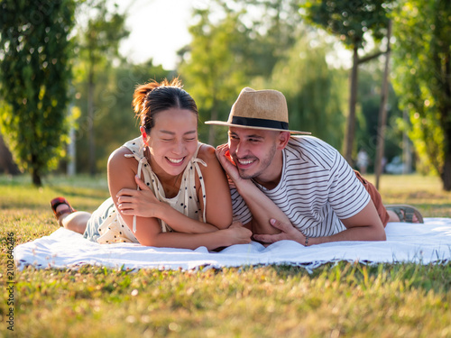 Cheerful multiracial couple is smiling and having fun in park in summertime.