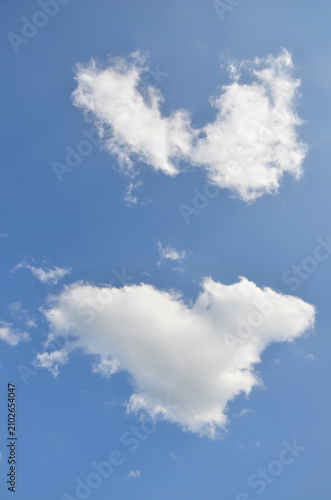 Bild auf Leinwand Two white clouds shaped like hearts against a clear blue sky create a playful and romantic visual effect
