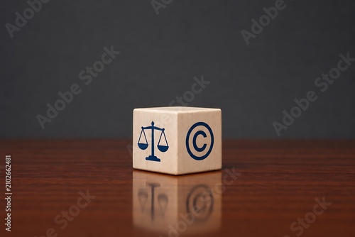Wooden cube with justice scales and copyright symbol on wooden surface