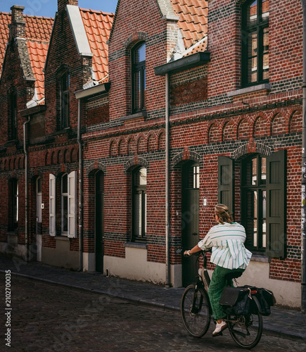 Woman Cycling Through a Historic Street in Bruges, Belgium