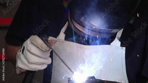 Welder performing manual arc welding process creating bright light flash in dark workshop