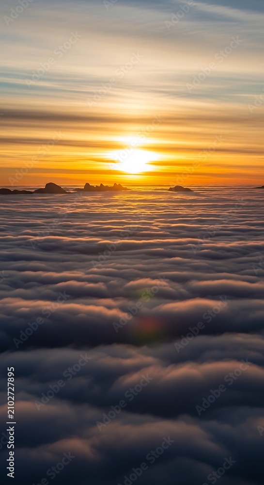 Obraz premium Bright sun glowing through clouds over sea of mist.