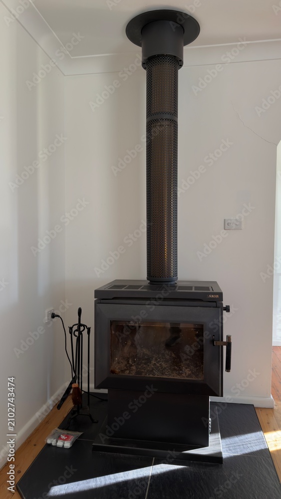 Obraz premium Modern Black Wood Burning Stove with Tall Flue in White Room