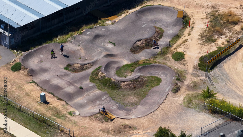 Fototapeta premium Aerial View of Cyclists on a Winding Asphalt Pump Track