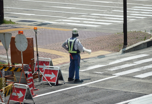 夏の昼の都市の街の道路工事現場で働く中年男性警備員の姿