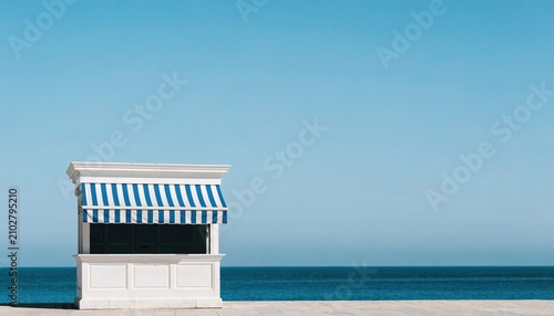 White beach kiosk with blue striped awning against clear sky