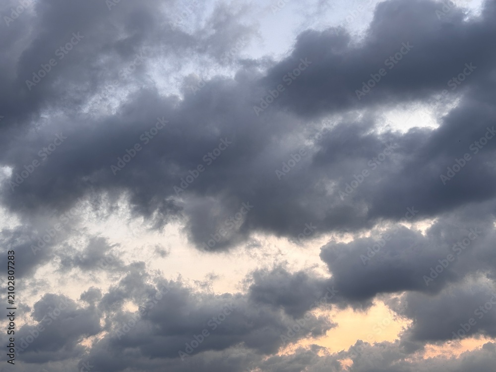 Obraz premium Beautiful dramatic sunset sky with dark fluffy clouds and soft orange gradient. Serene atmospheric twilight landscape with ample copy space.