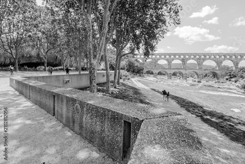 two individuals walking along a pathway near a roman aqueduct 