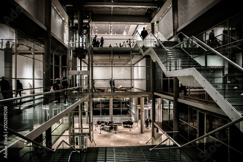 people ascending and descending modern staircase in glass railings 