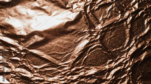 Abstract Bronze Foil Texture Close Up with Dim Lighting Reflecting Various Highlights and Shadows in the Wrinkled Surface
