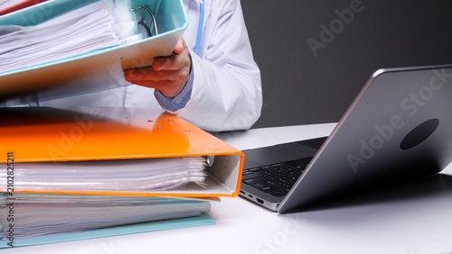 Canvastavla Healthcare worker organizing a stack of binders filled with patient documents wh