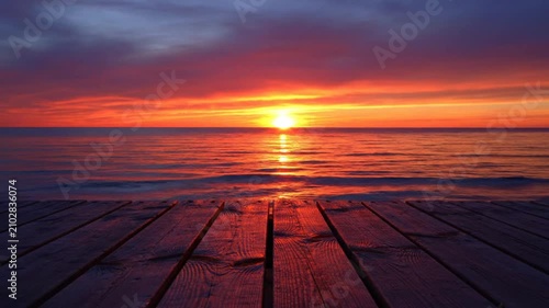 Stunning sunset view with vibrant colors over the calm ocean reflecting on the wooden pier