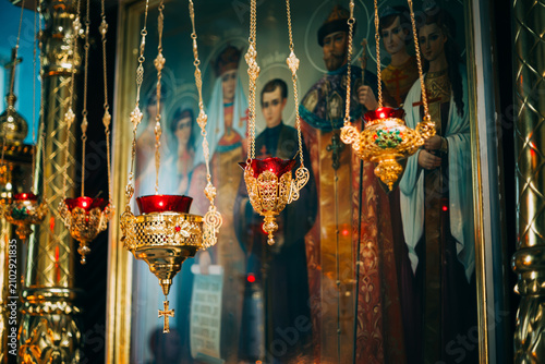 Фотография Golden Orthodox icon lamps hanging before an icon of Tsar Nicholas II's family