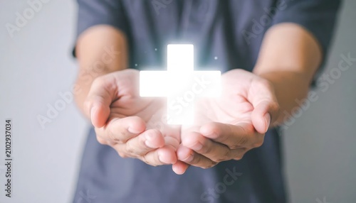 Person holding a glowing white medical cross icon.