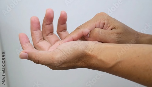 Person massaging palm of hand for pain relief.