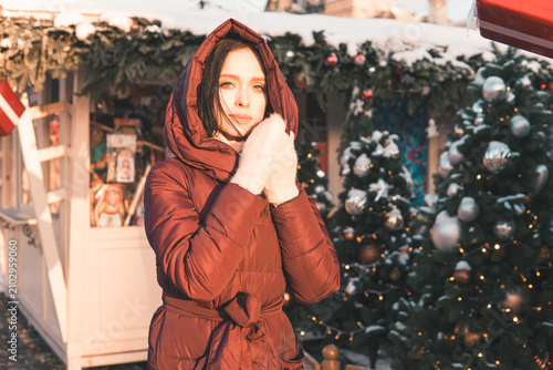 Canvas Print Woman wearing a warm red coat and white mittens adjusting Christmas tree ornaments