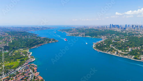 Istanbul, Turkey. Red and blue cargo ship sails through the Bosphorus. City panorama. Strait between Europe and Asia. Sunny day, Aerial View
