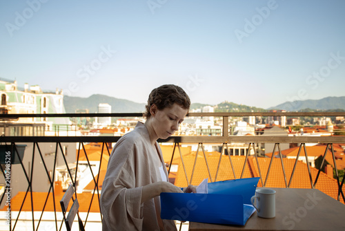 woman in cancer recovery reviews medical documents in a blue folder on a sunny terrace, organizing treatment records, insurance papers and follow up care while traveling