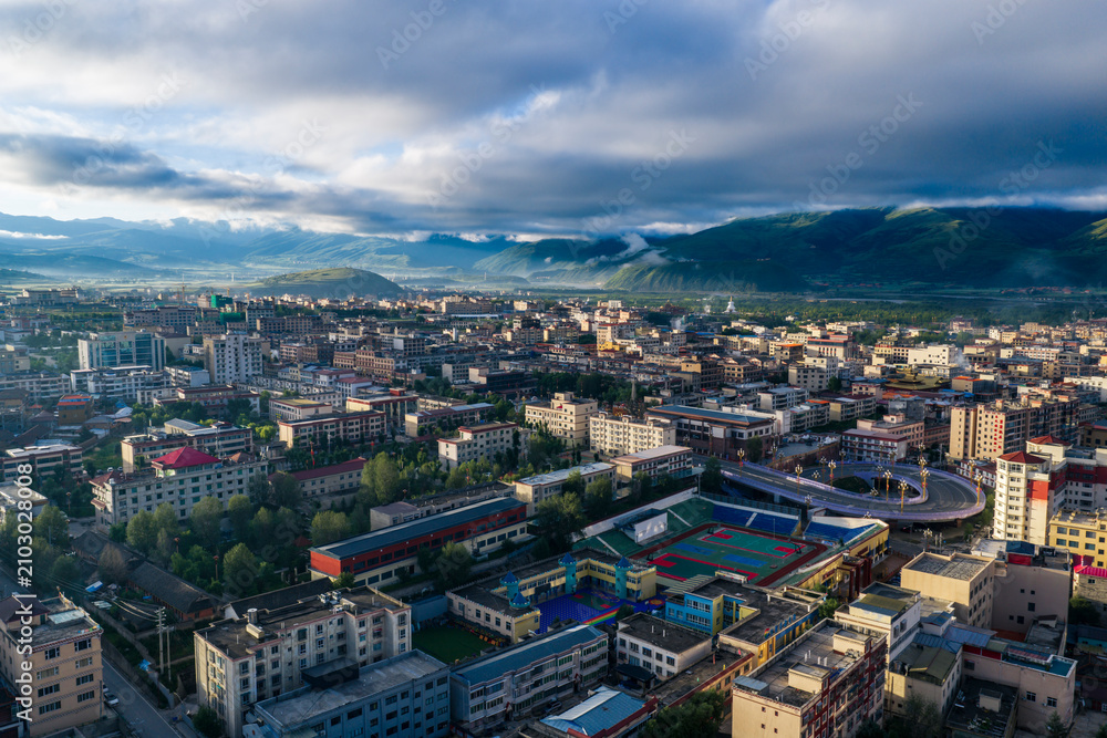 Obraz premium Aerial panoramic view of Garzê County at sunrise, Tibetan town by Yalong River, Garzê Temple white stupa, mountain plateau city morning landscape in West Sichuan