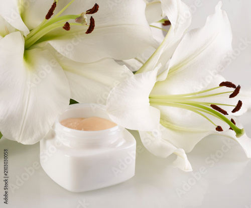Jar of Face Cream with White Lily on Clean Surface