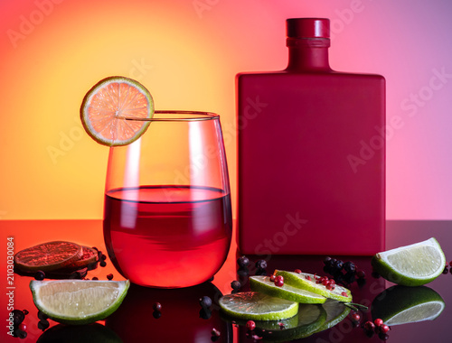 Vibrant Red Cocktail with Gin Bottle and Citrus Garnish