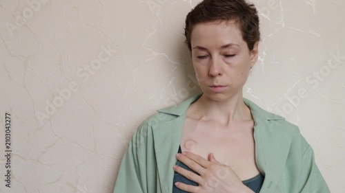 portrait of a woman with a visible port and open overshirt leaning against a wall, expressing survivorship, body confidence and life after chemotherapy