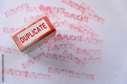 фотографія Red duplicate rubber stamp on white paper surrounded by multiple faded red stamp marks, top view