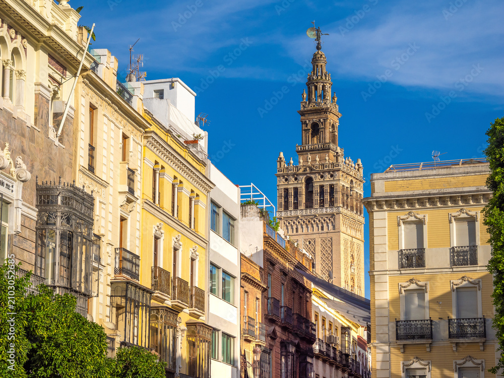 Fototapeta premium Streets of the old town of Seville with the iconic Giralda bell tower of the Cathedral in the background, Seville, Andalusia, Spain