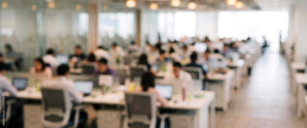 Obraz premium A modern office space bustling with employees working at their desks, surrounded by bright lighting and a spacious layout, creating a vibrant work atmosphere.