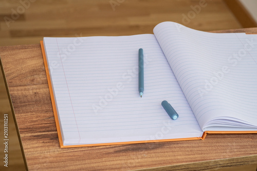 Open lined notebook with pen on a wooden desk