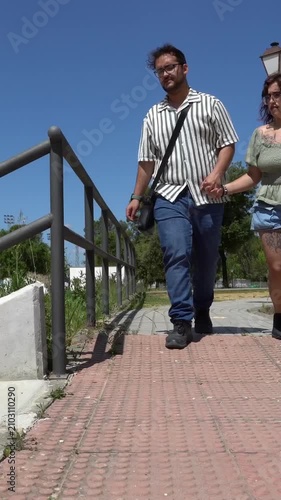 Young couple holding hands and walking in a park. The woman, an amputee with a prosthetic leg, walks confidently alongside her supportive partner