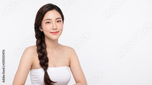 young woman with long dark braided hairstyle, natural makeup, wearing a white strapless tube top, sitting elegantly, with a soft smile, isolated on a white seamless studio background