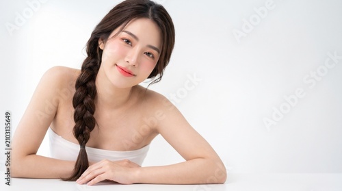young woman with long dark braided hairstyle, natural makeup, wearing a white strapless tube top, lying gracefully, with a relaxed expression, isolated on a white seamless studio background