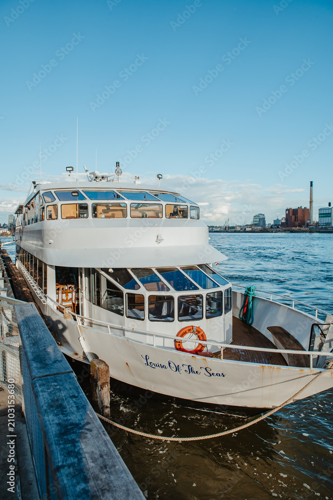 Fototapeta premium New York, USA, 22 April 2026: Louisa Of The Seas boat docked at New York harbor. White passenger vessel Louisa Of The Seas moored at a pier in New York City with East River background.