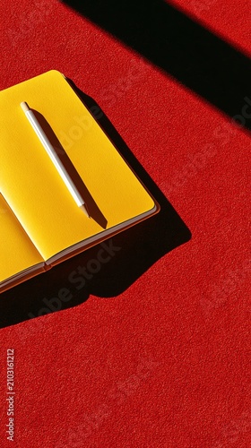 A vibrant yellow notebook on red surface.