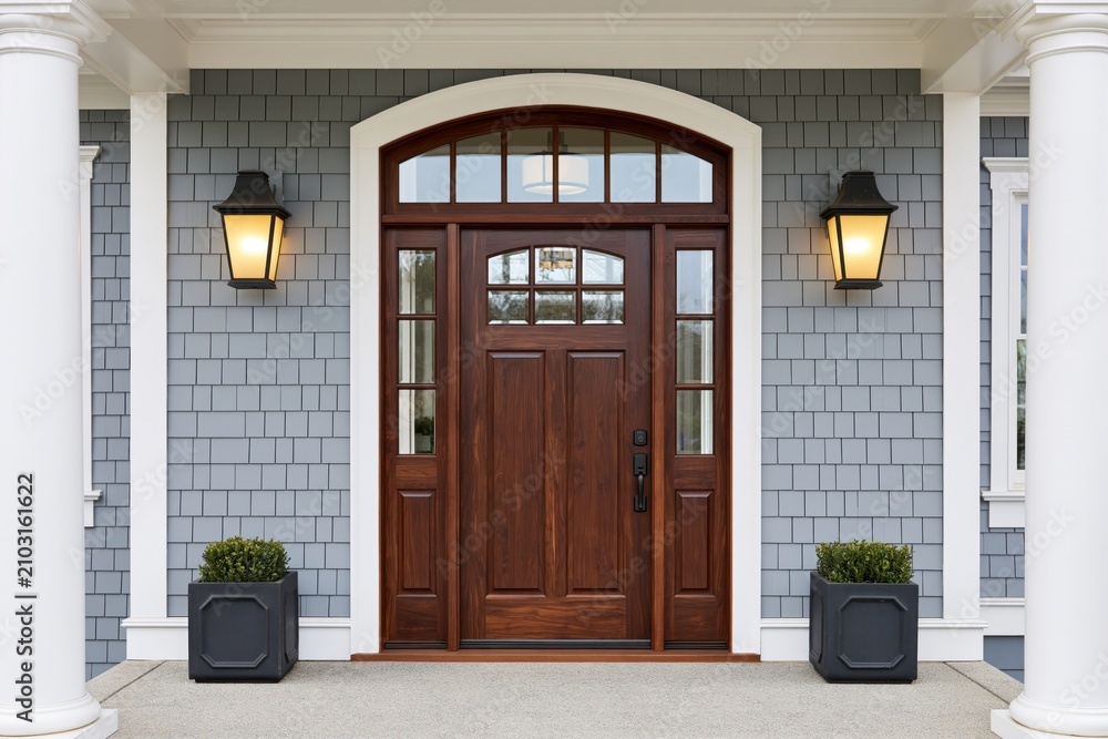 Obraz premium The Wooden Front Door Framed by Arched Transom, Lanterns, and Columns