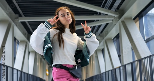 Full length urban trendsetter striking pose, colorful skirt and fanny pack, varsity jacket layered for contrast, confident playful energy, low angle perspective, streetwear aesthetic, vibrant content
