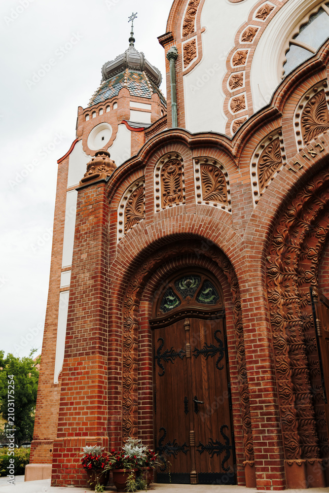 Obraz premium Ornate brick entrance portal with carved decorative details at the historic synagogue. Fine craftsmanship highlighting the Art Nouveau architecture of Subotica, Serbia.